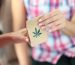 Woman give to buyer paper bag of drugs. Marijuana leaf close-up on paper bag.